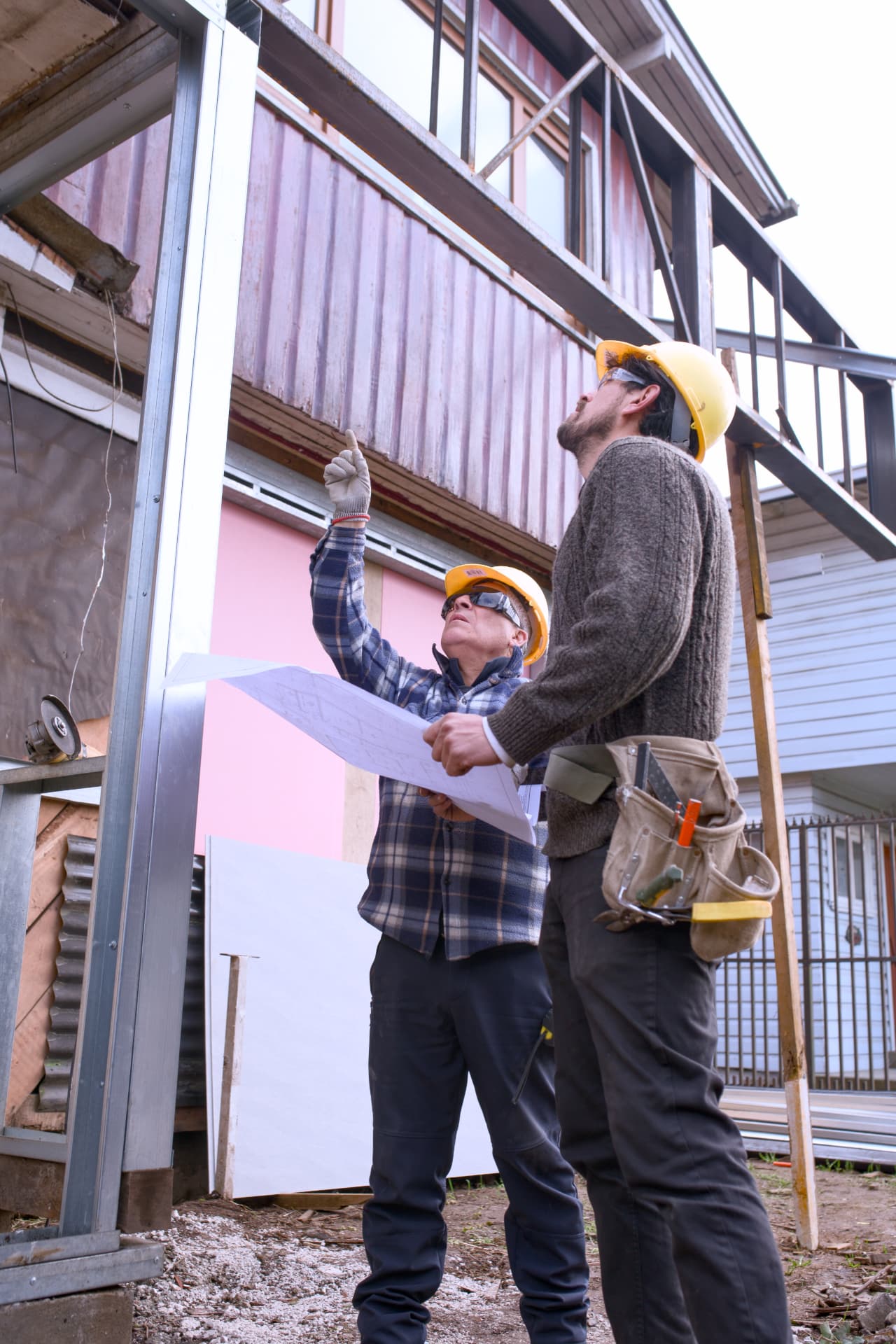 Dos profesionales con casco revisando planos y estructura en terreno